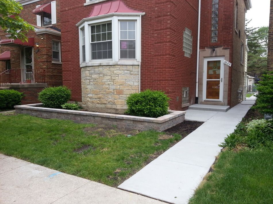 A brick house with a concrete walkway leading to the front door