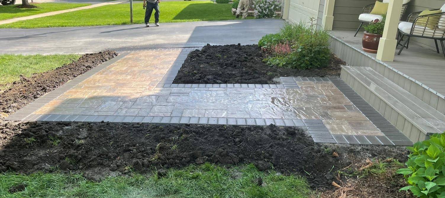 A brick walkway is being built in front of a house.