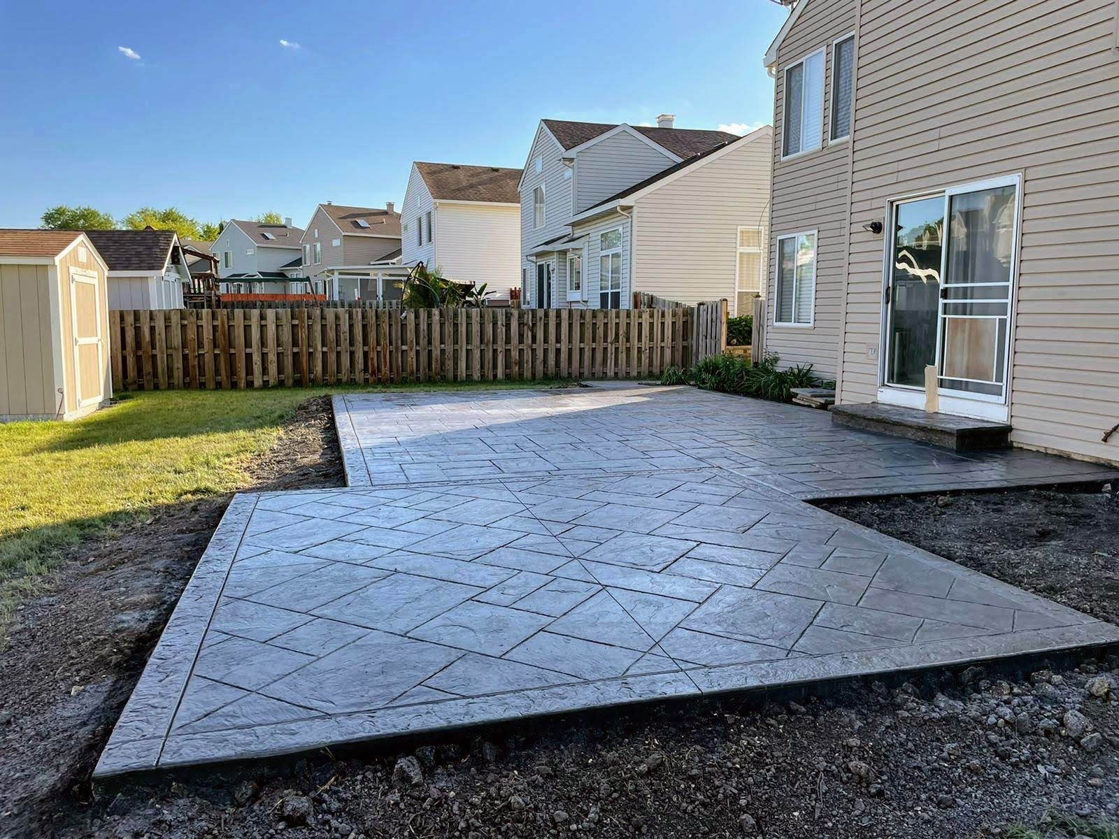 A concrete patio is being built in the backyard of a house.