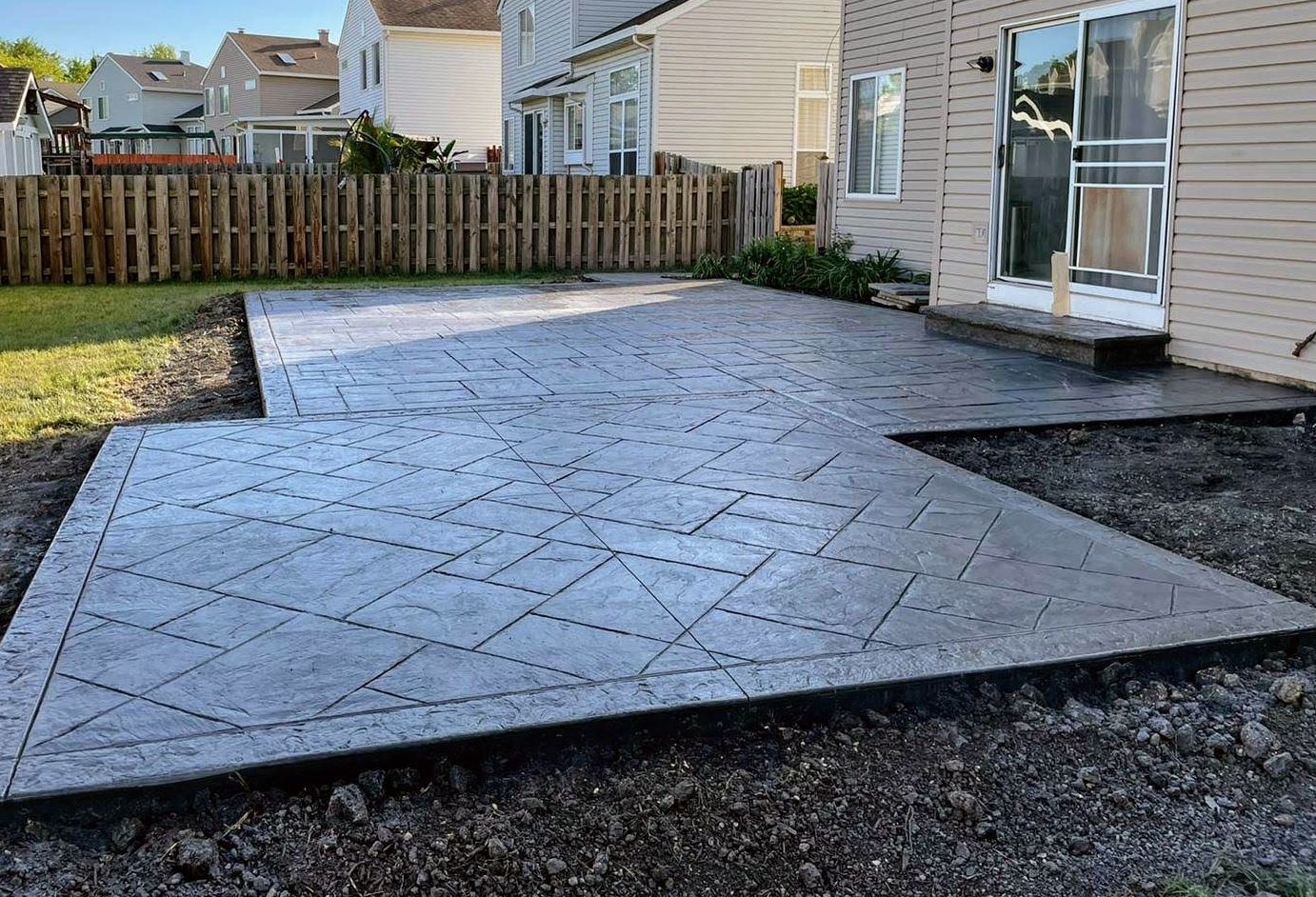 A concrete patio is being built in the backyard of a house.