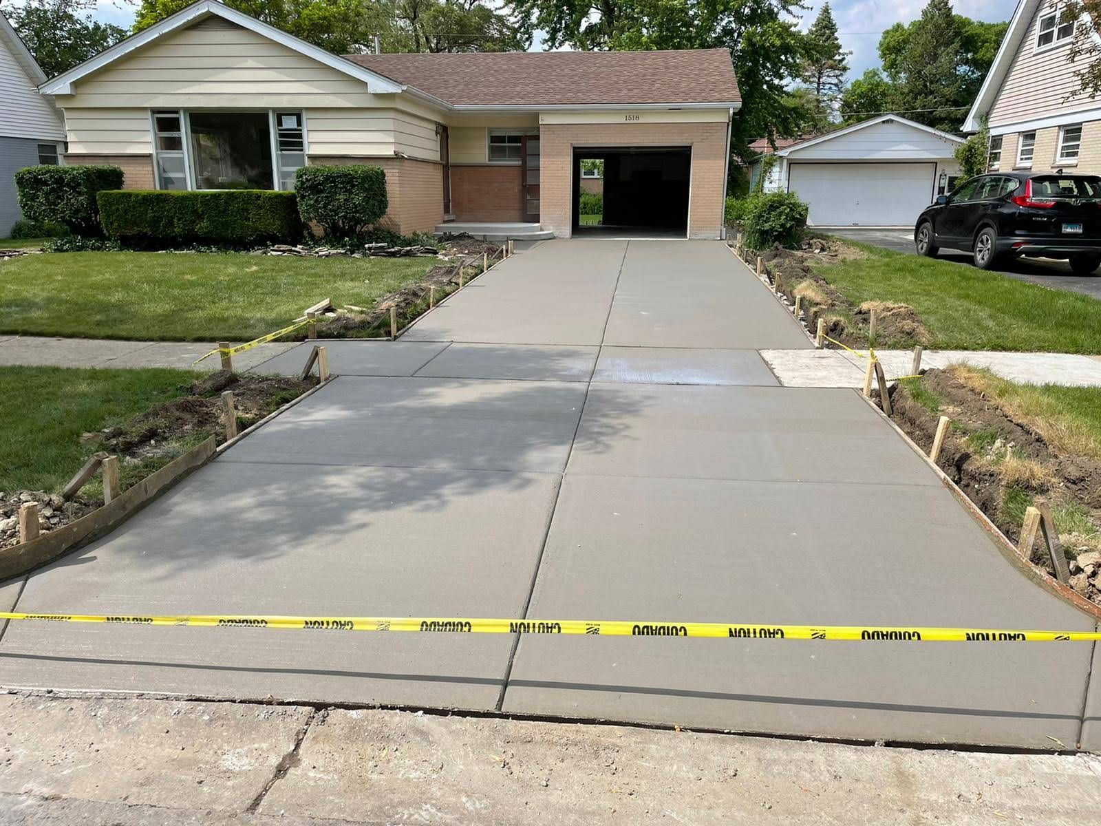 A concrete driveway is being built in front of a house