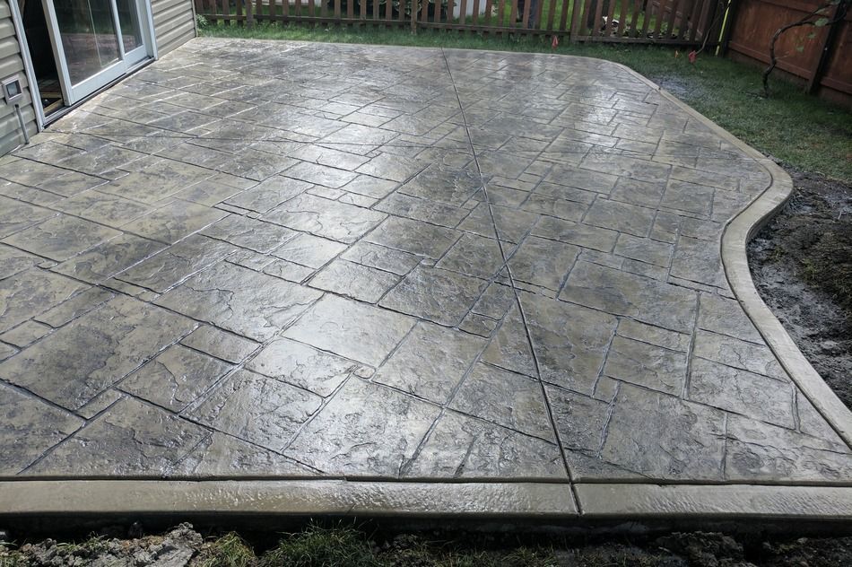 A concrete patio with a diagonal pattern and a fence in the background.