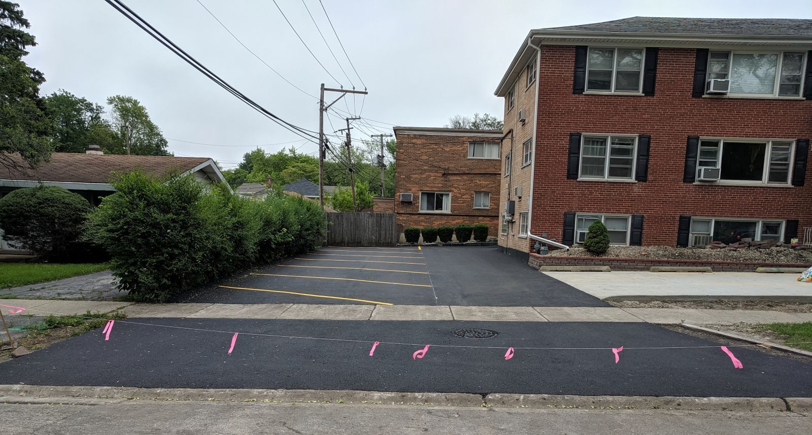 A man is working on a brick driveway in front of a brick house.