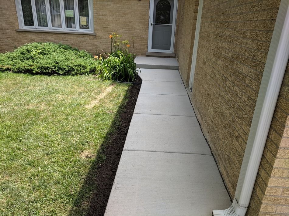 A concrete walkway leading to the front door of a brick house.