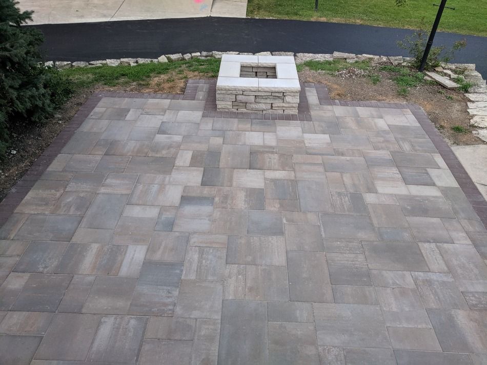 A patio with a fire pit in the middle of it.