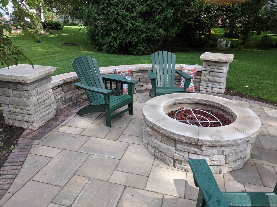 Two green chairs are sitting around a fire pit on a patio.