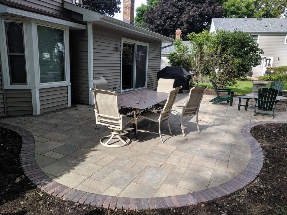 A patio with a table and chairs in front of a house.