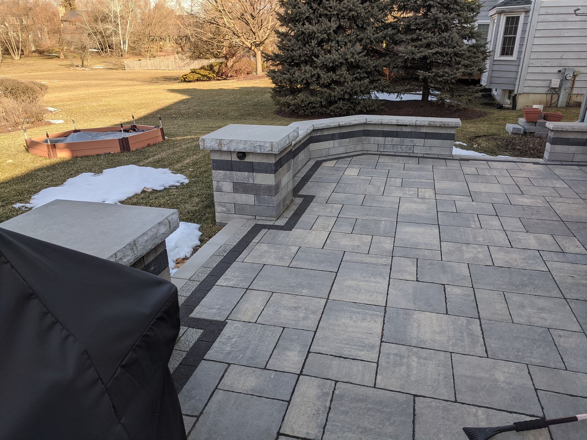 A patio with a black cover on it and a fire pit in the background.