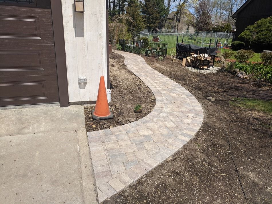 A brick walkway is being built in front of a garage.