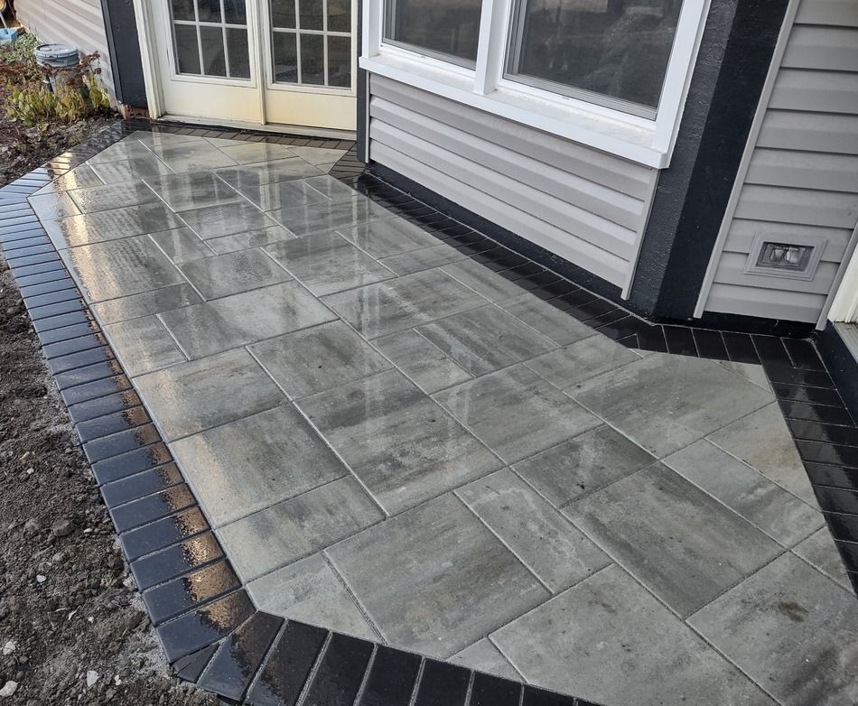 A patio with tiles and bricks in front of a house.