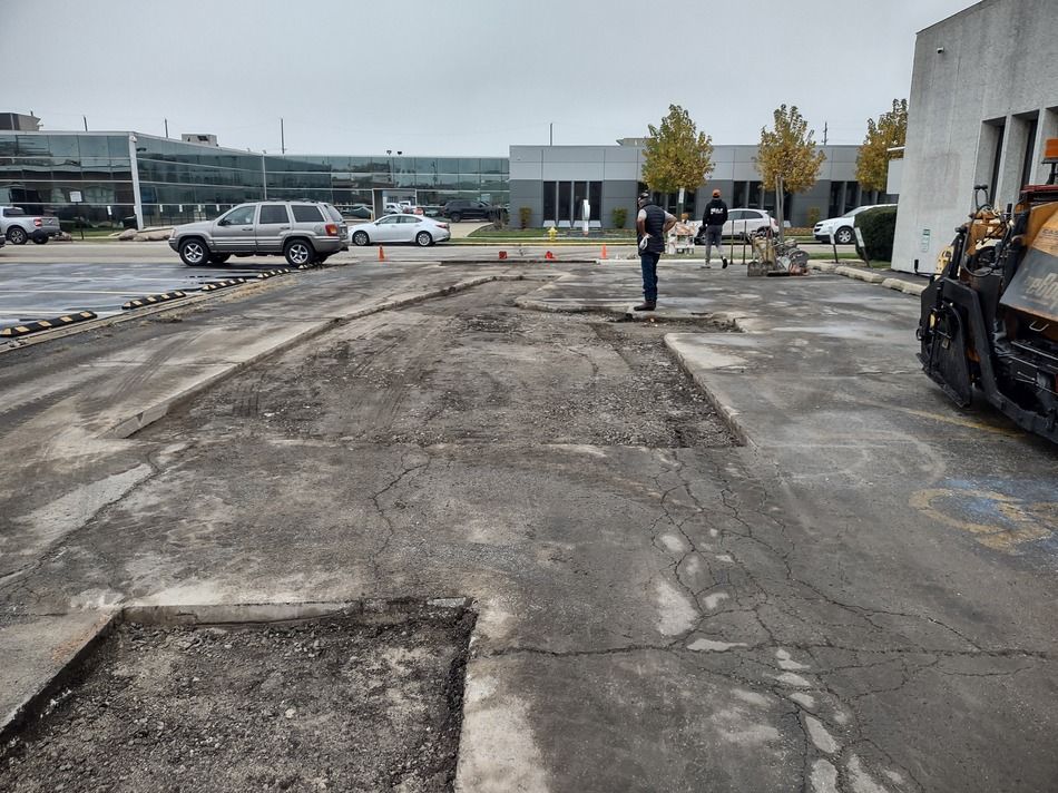 A man is standing in a parking lot in front of a building.