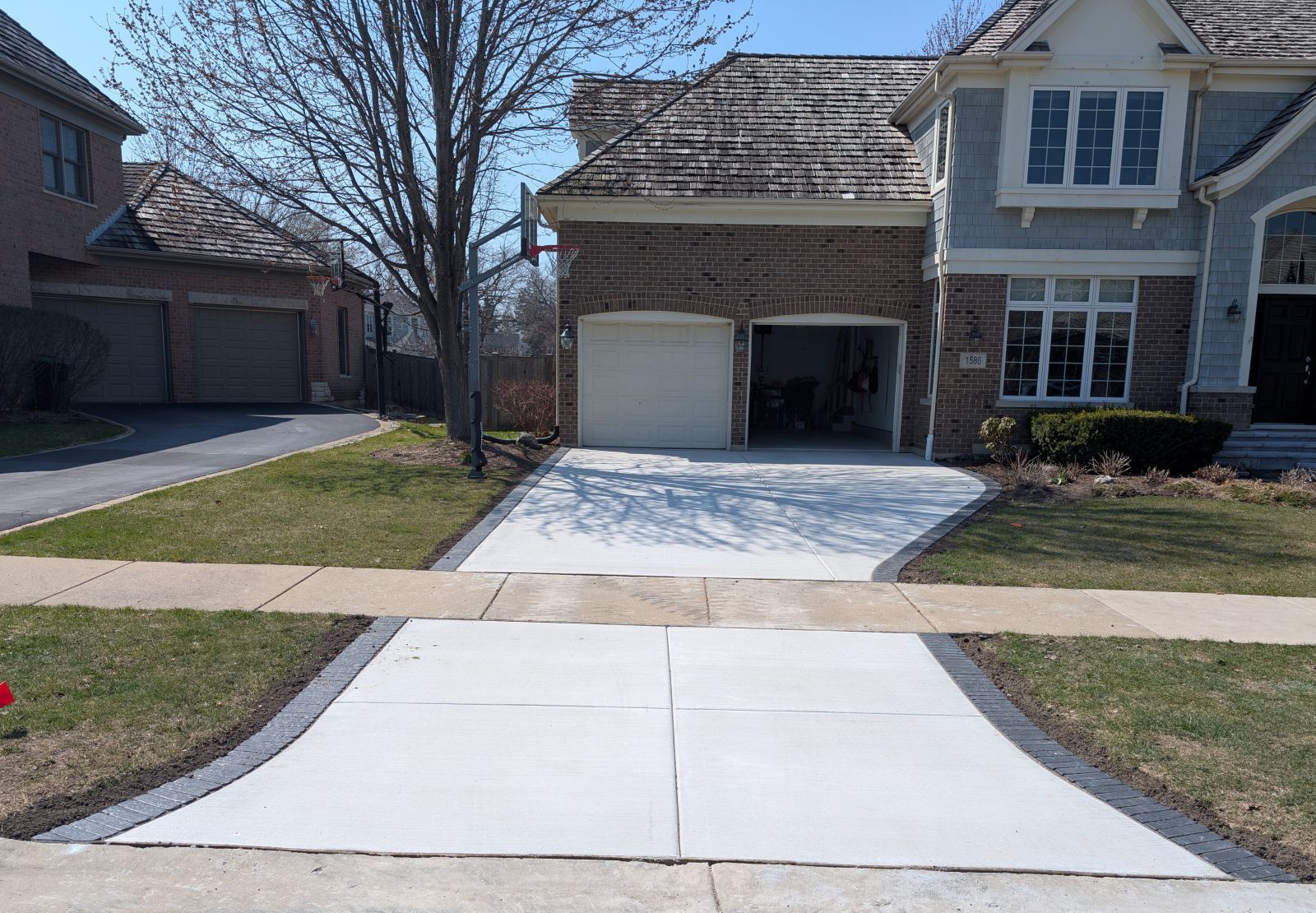 Driveway leading to a two-car garage of a house, with green grass on either side.