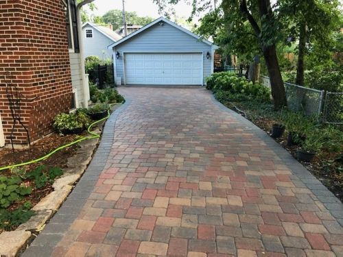 A brick driveway leading to a garage next to a brick house.