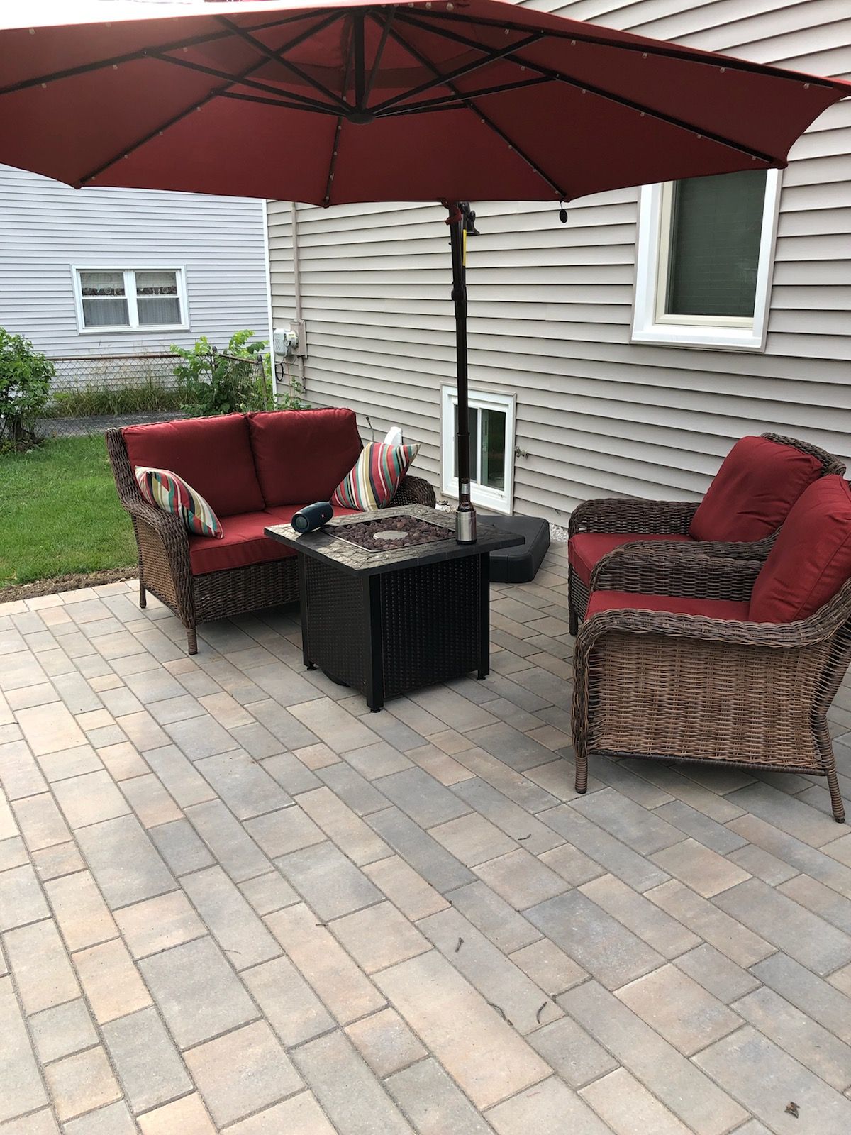 A patio with a couch , chairs , table and umbrella.