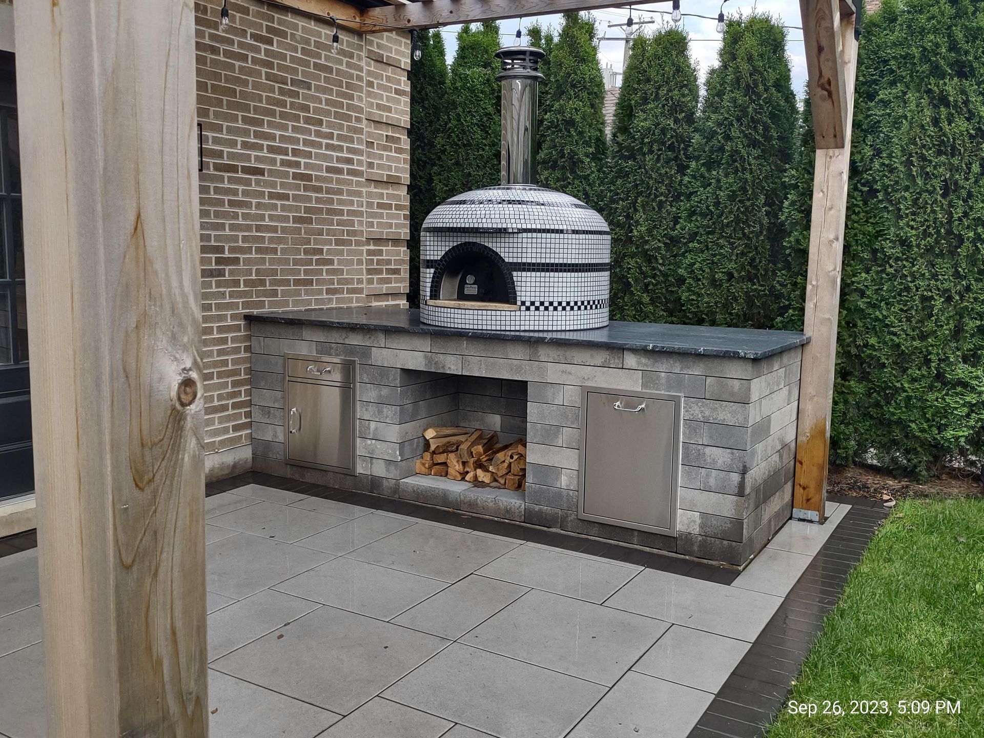 A pizza oven is built into the side of a brick building.