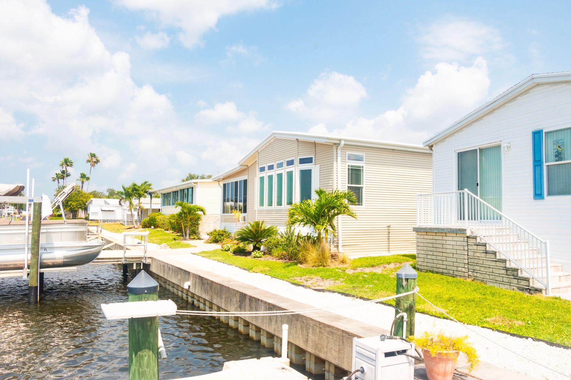 Seawall inspection at Florida waterfront mobile homes with palm trees, calm water, and clear skies.