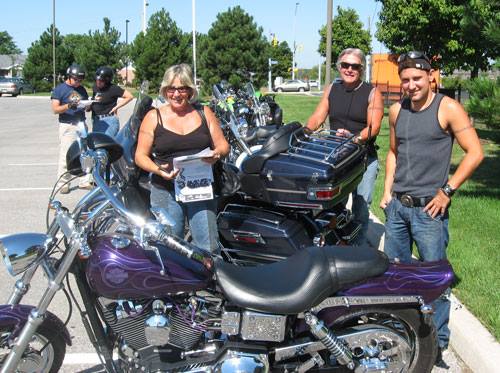 3 ride participants posed with a motorcycle