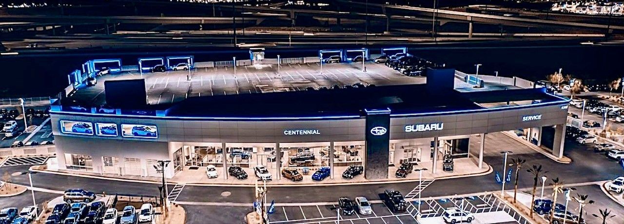 An aerial view of a large building at night with a lot of cars parked in front of it.