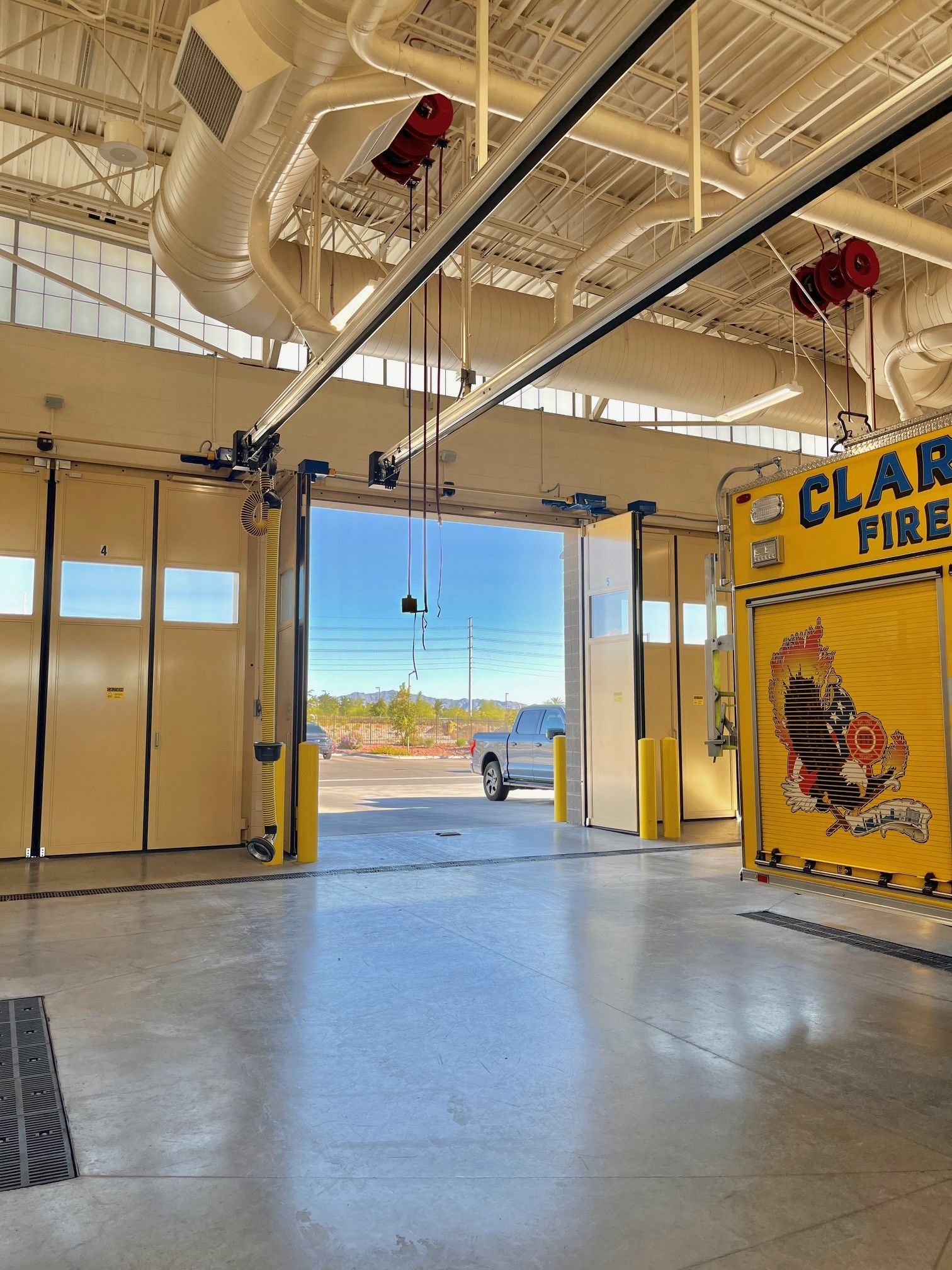 A fire station with the doors open and a truck parked in the background.