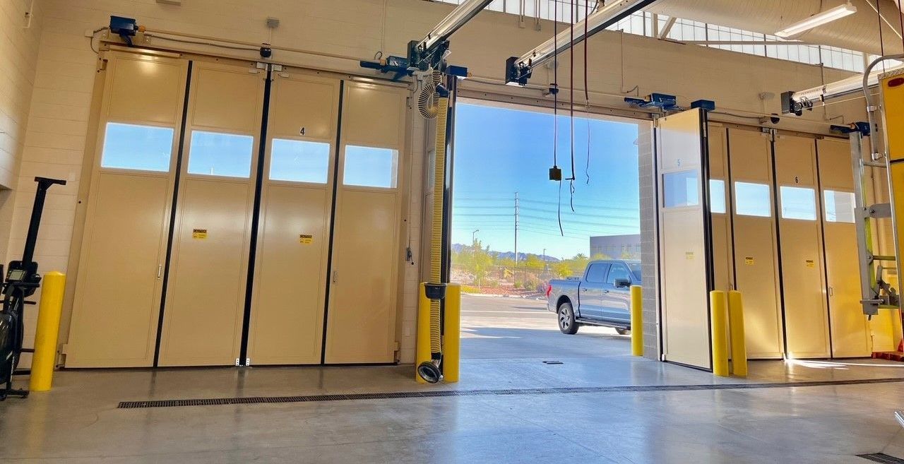 A white truck is parked in a garage with the doors open.