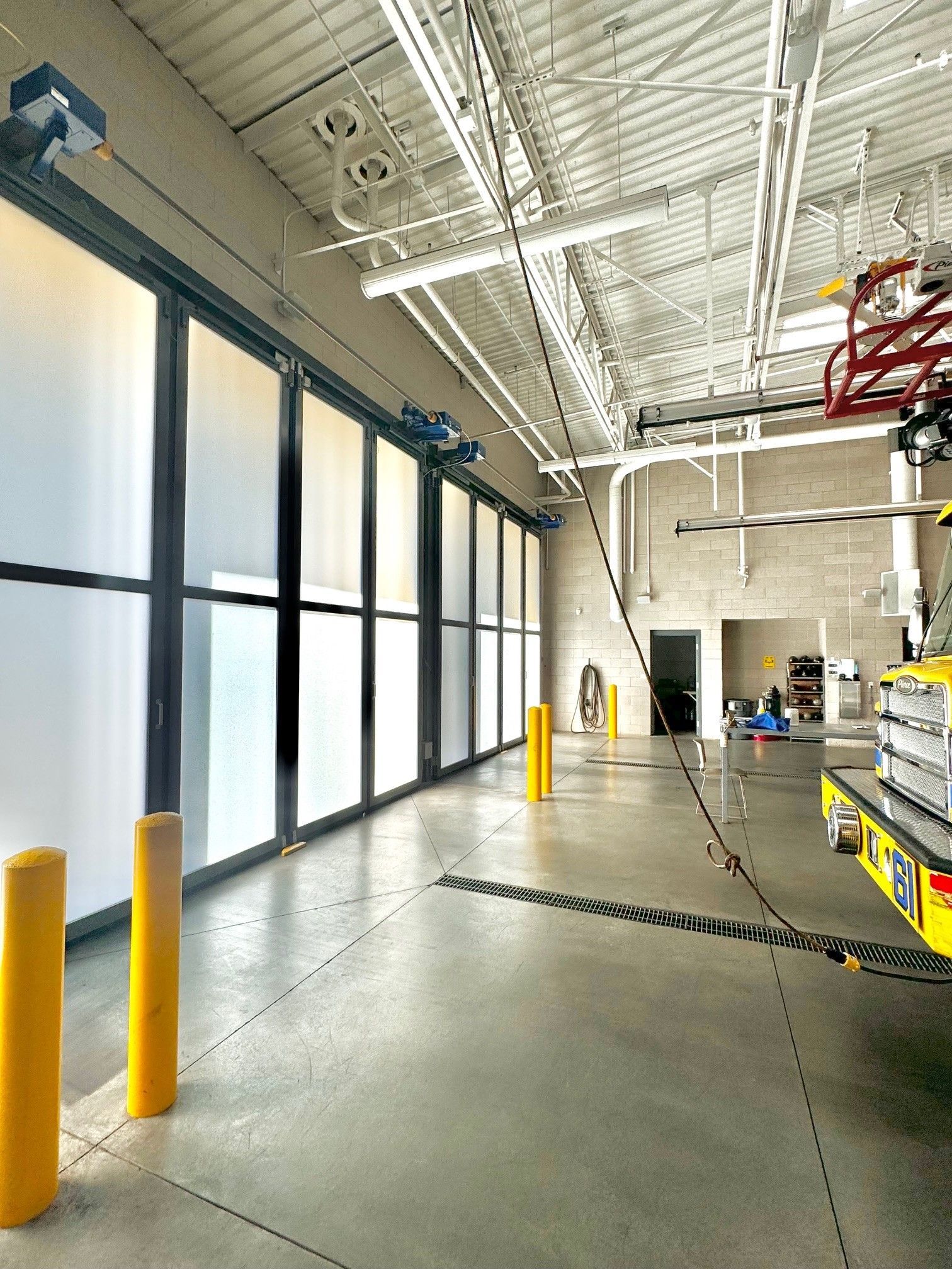 A fire truck is parked in a garage with a lot of windows.