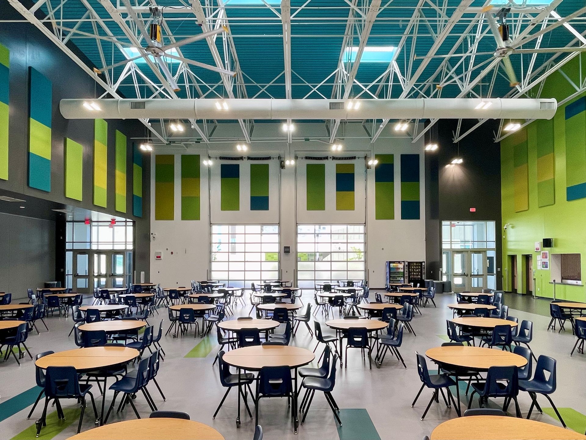 A large room filled with tables and chairs in a school cafeteria.