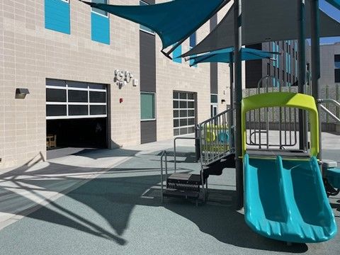 A playground with a slide and stairs in front of a building