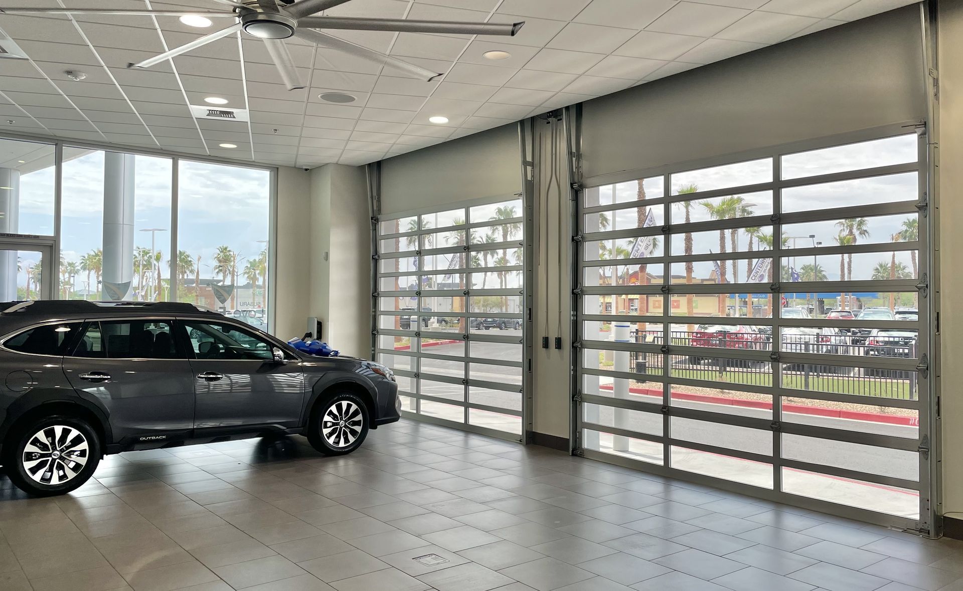 A car is parked in a showroom next to a garage door.