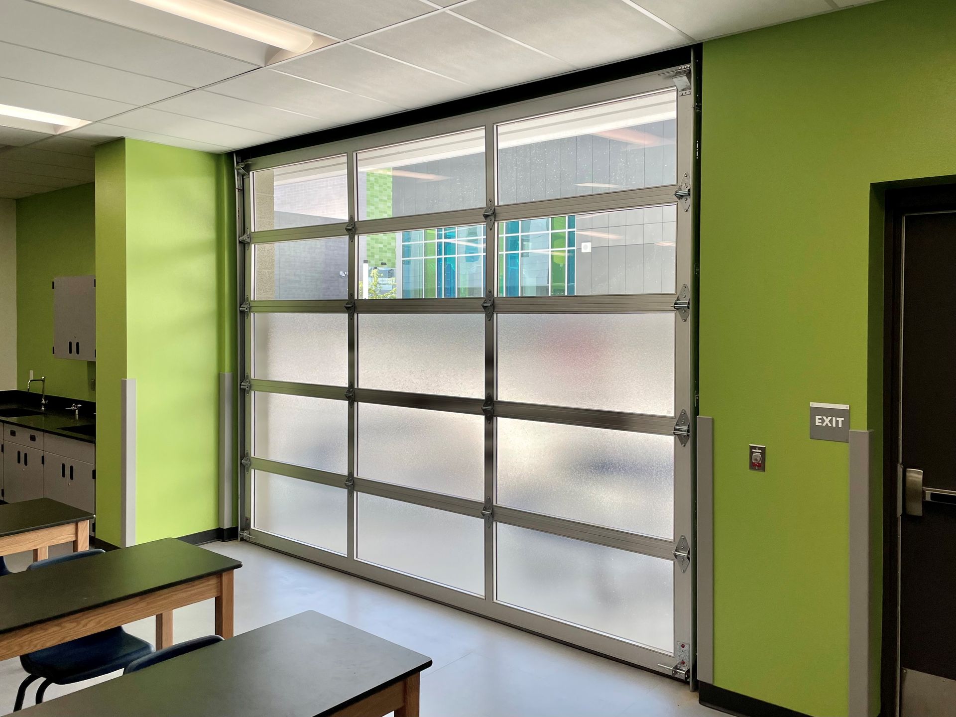 A classroom with green walls and a large glass garage door.