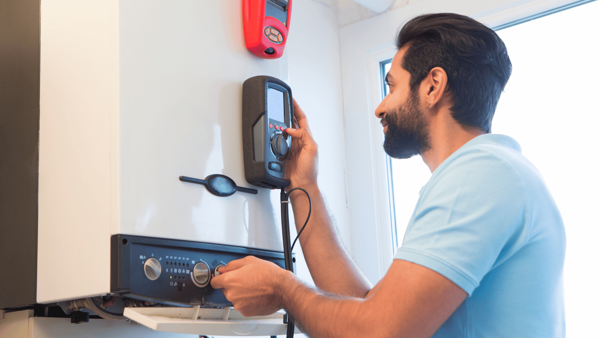 A man is fixing a boiler with a digital thermometer.