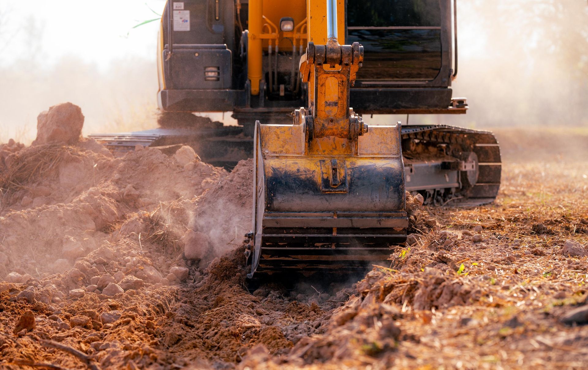 Low angle view of earthmoving machinery excavating at a construction site, digging a trench.