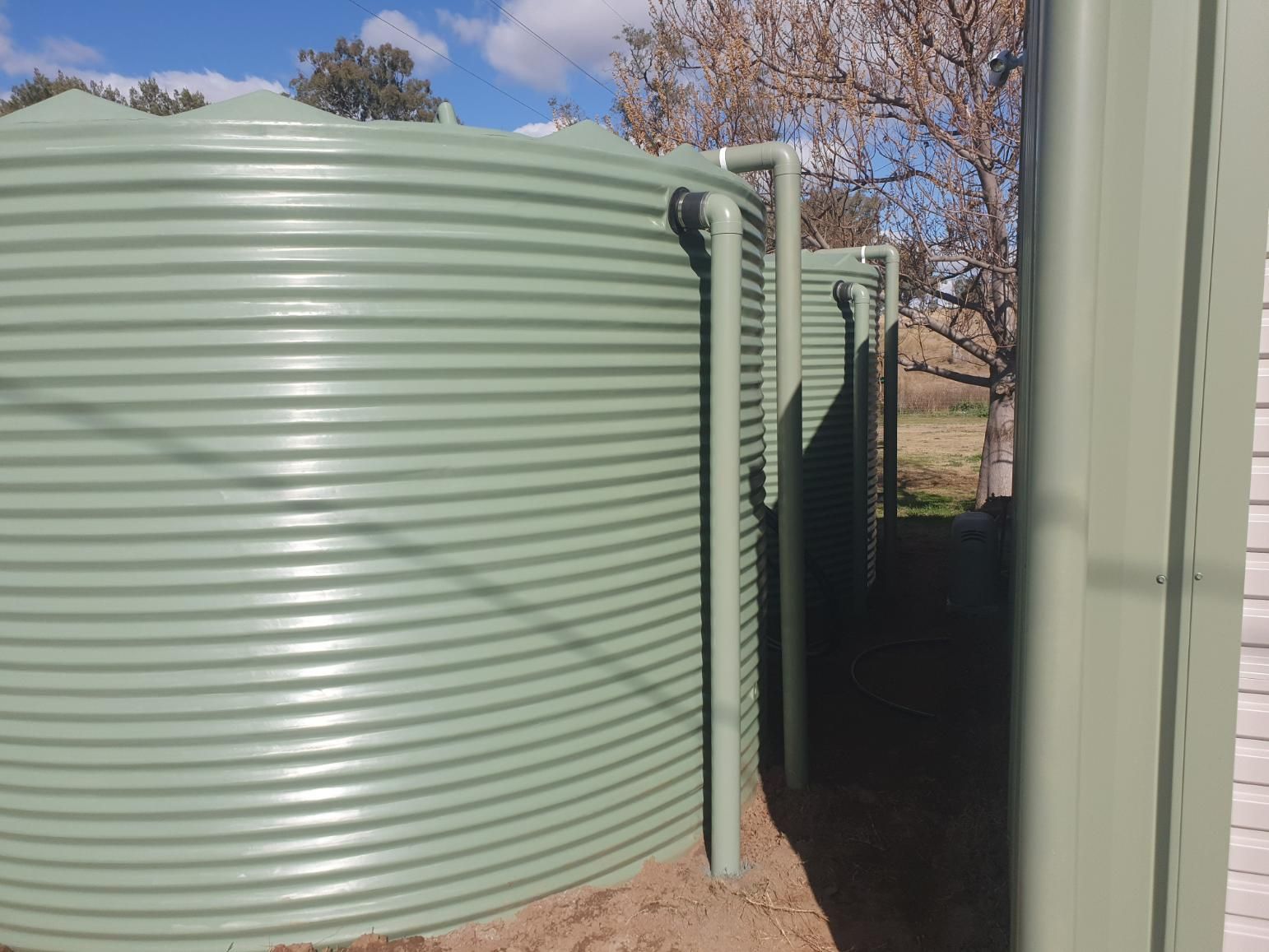Row of Green Water Tanks Are Lined Up Next to Each Other — Peel Irrigation & Water Supplies in Gunnedah, NSW