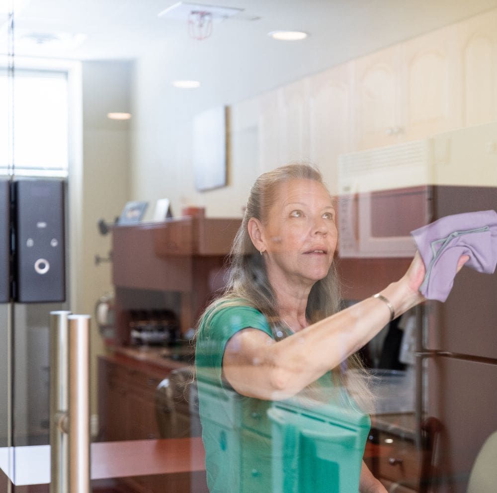 a member of the sparkling green team cleaning the kitchen and breakroom of the office