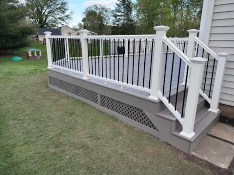 White deck railing and stairs attached to a house with a lattice skirting panel underneath.