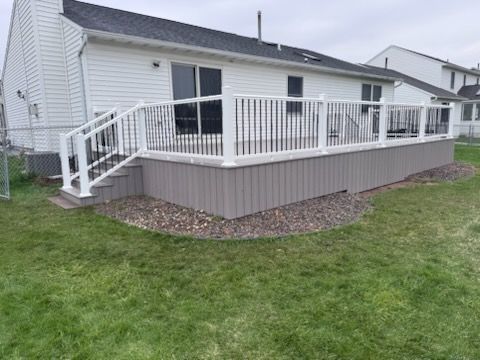 House deck with white railing and steps over a grassy backyard