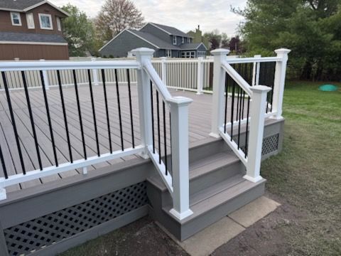 White-railed wooden deck steps with dark cable railing leading to a backyard yard, with house and trees nearby