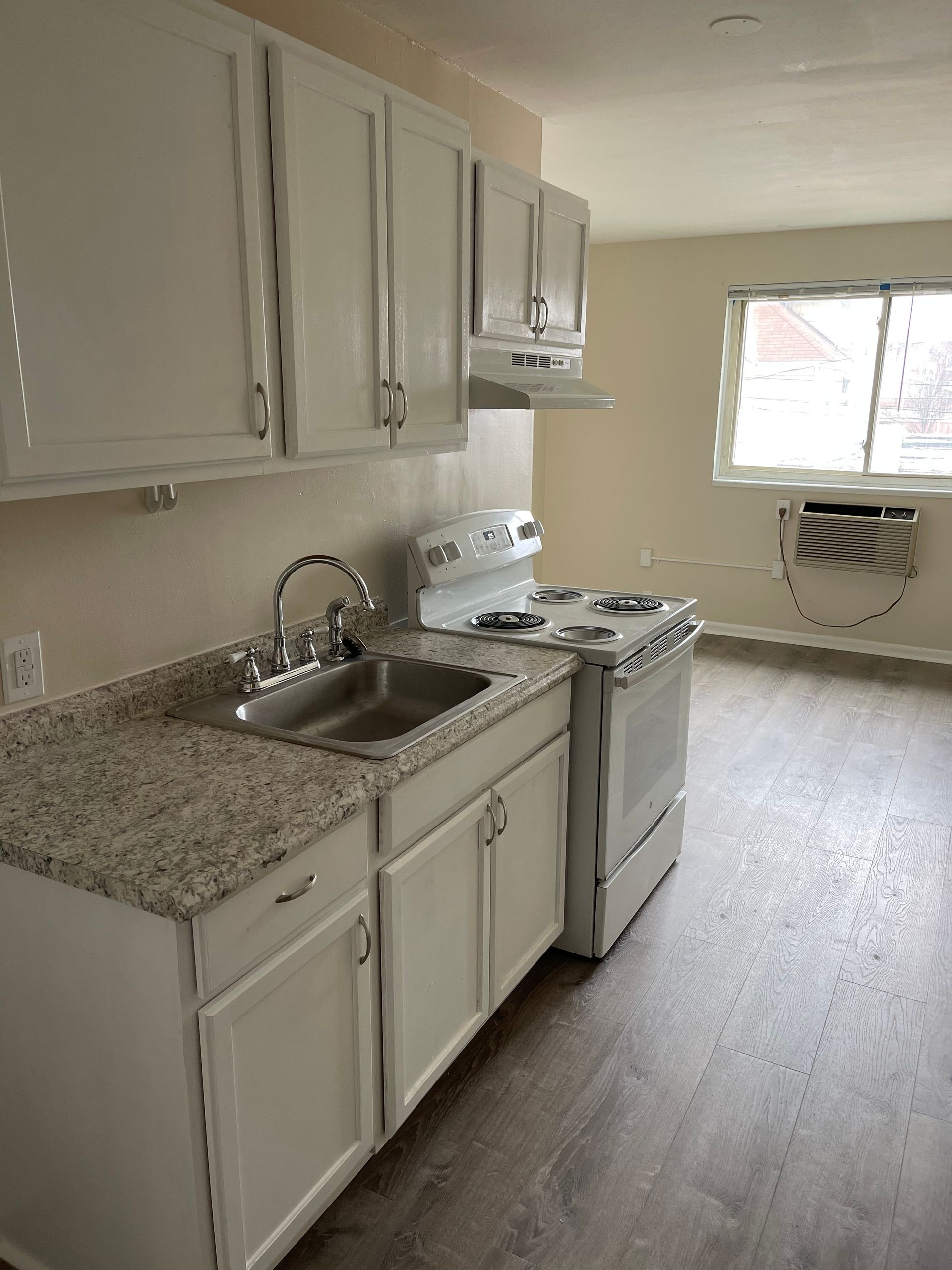 A kitchen with white cabinets , granite counter tops , a stove and a sink.