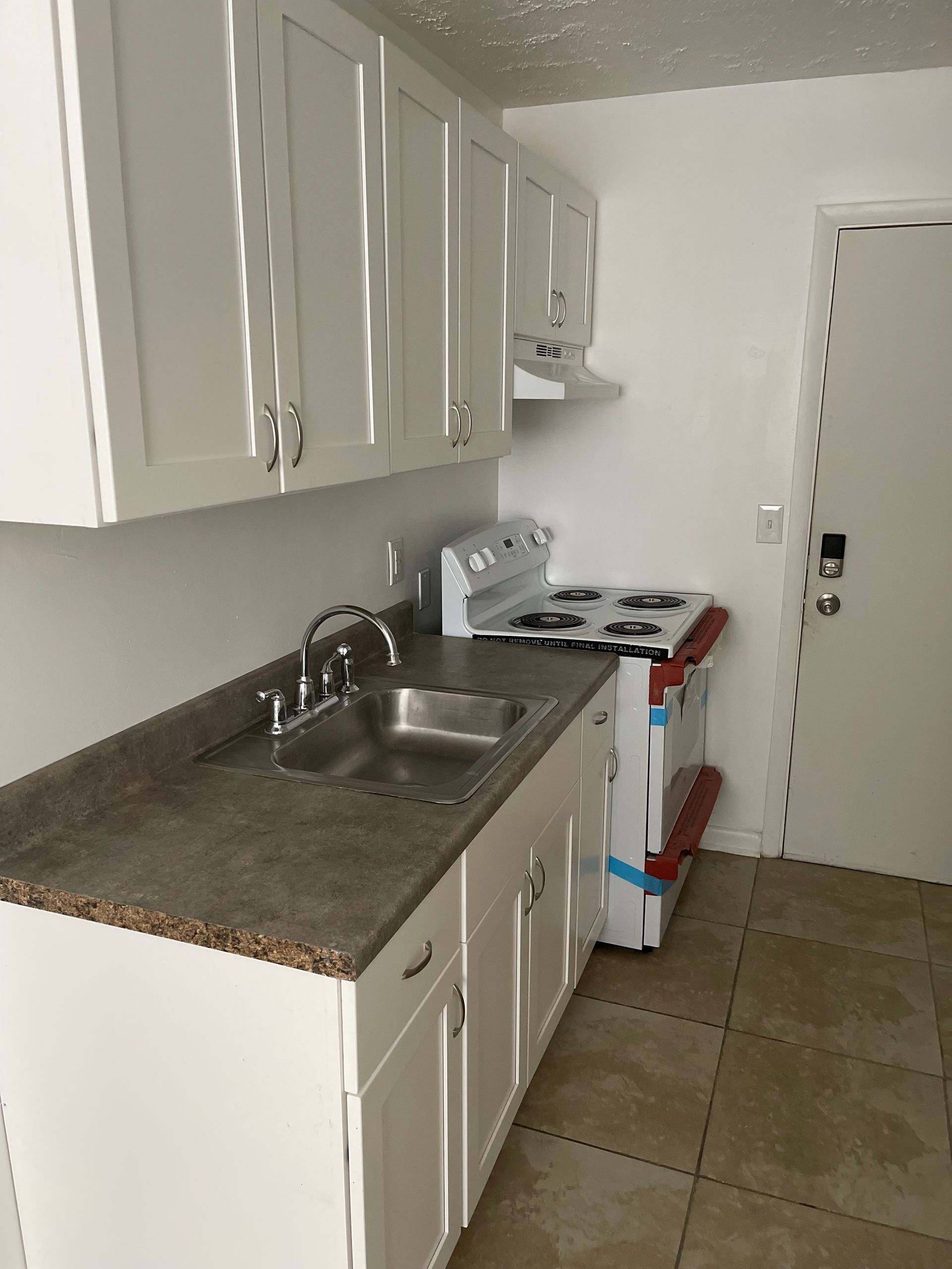 A kitchen with white cabinets and a sink and stove