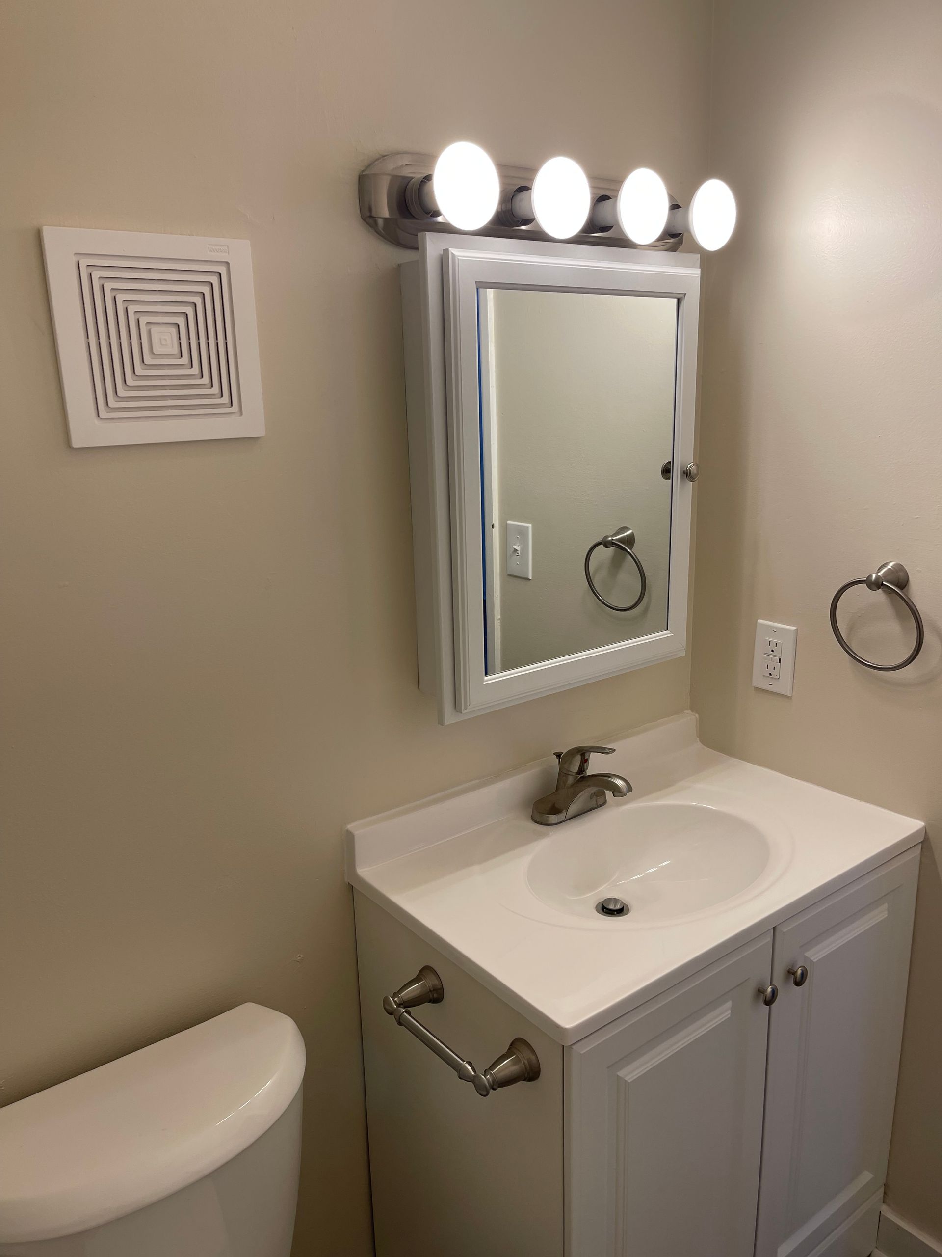 A bathroom with a sink , toilet and mirror.