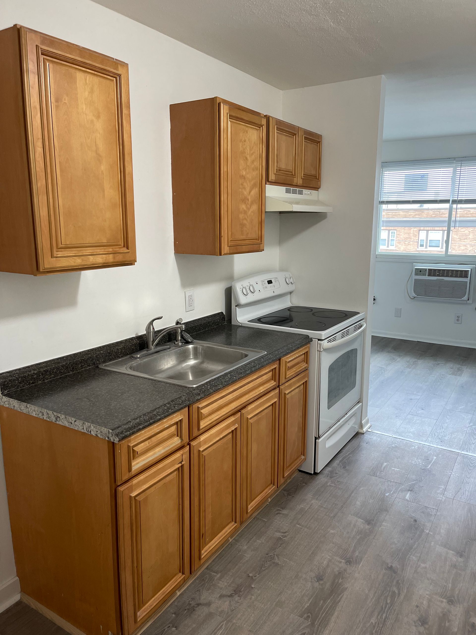 A kitchen with wooden cabinets , a stove and a sink