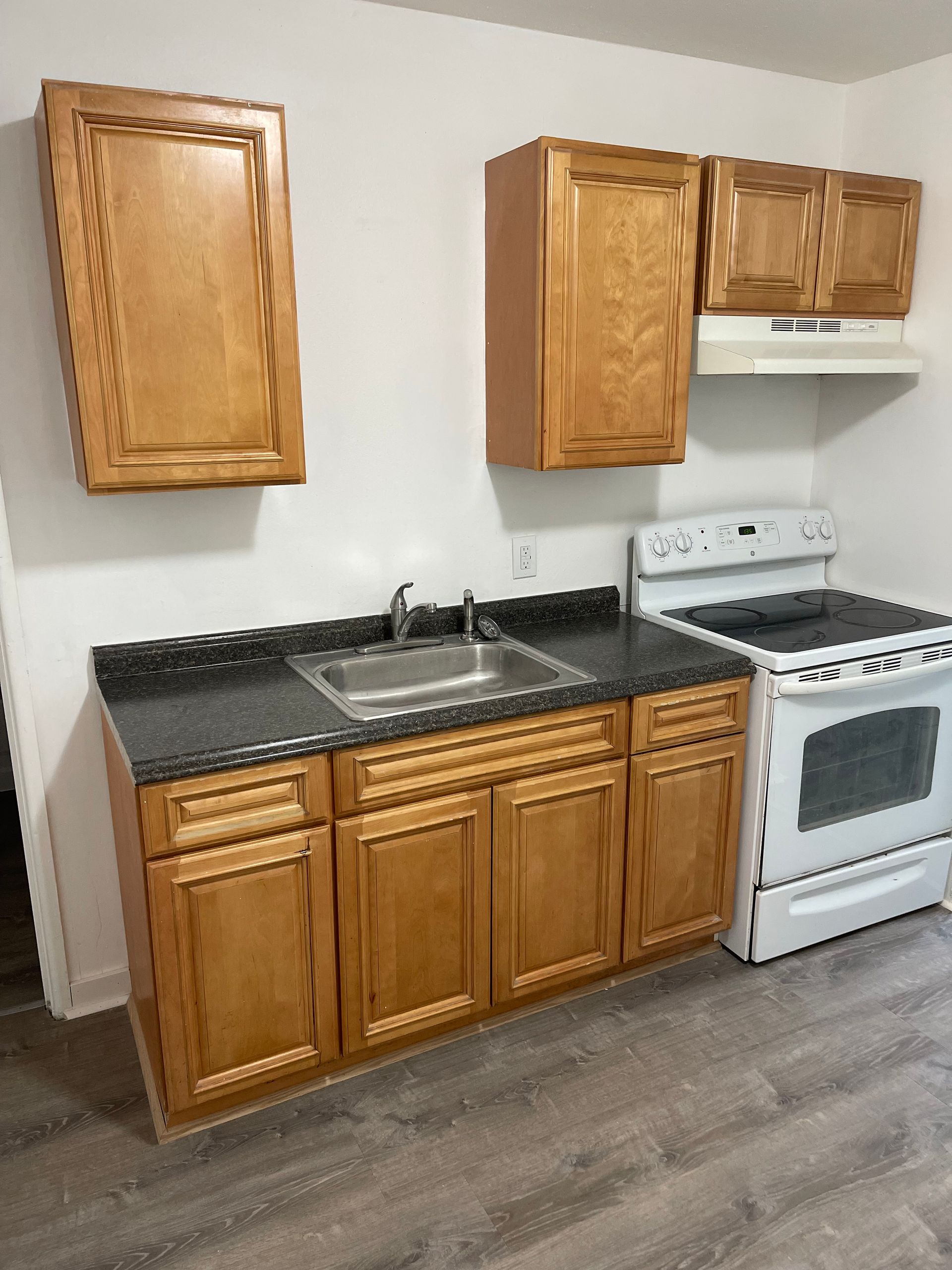 A kitchen with wooden cabinets and a stove and sink