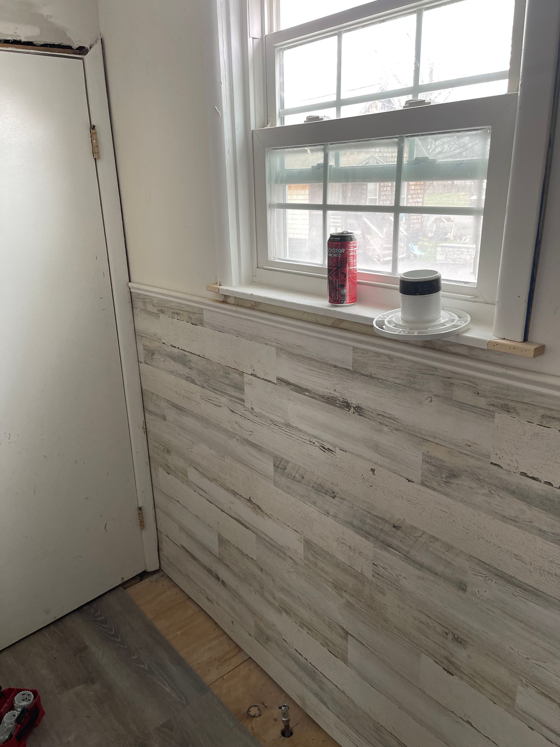 A room with a white wooden wall and a window.