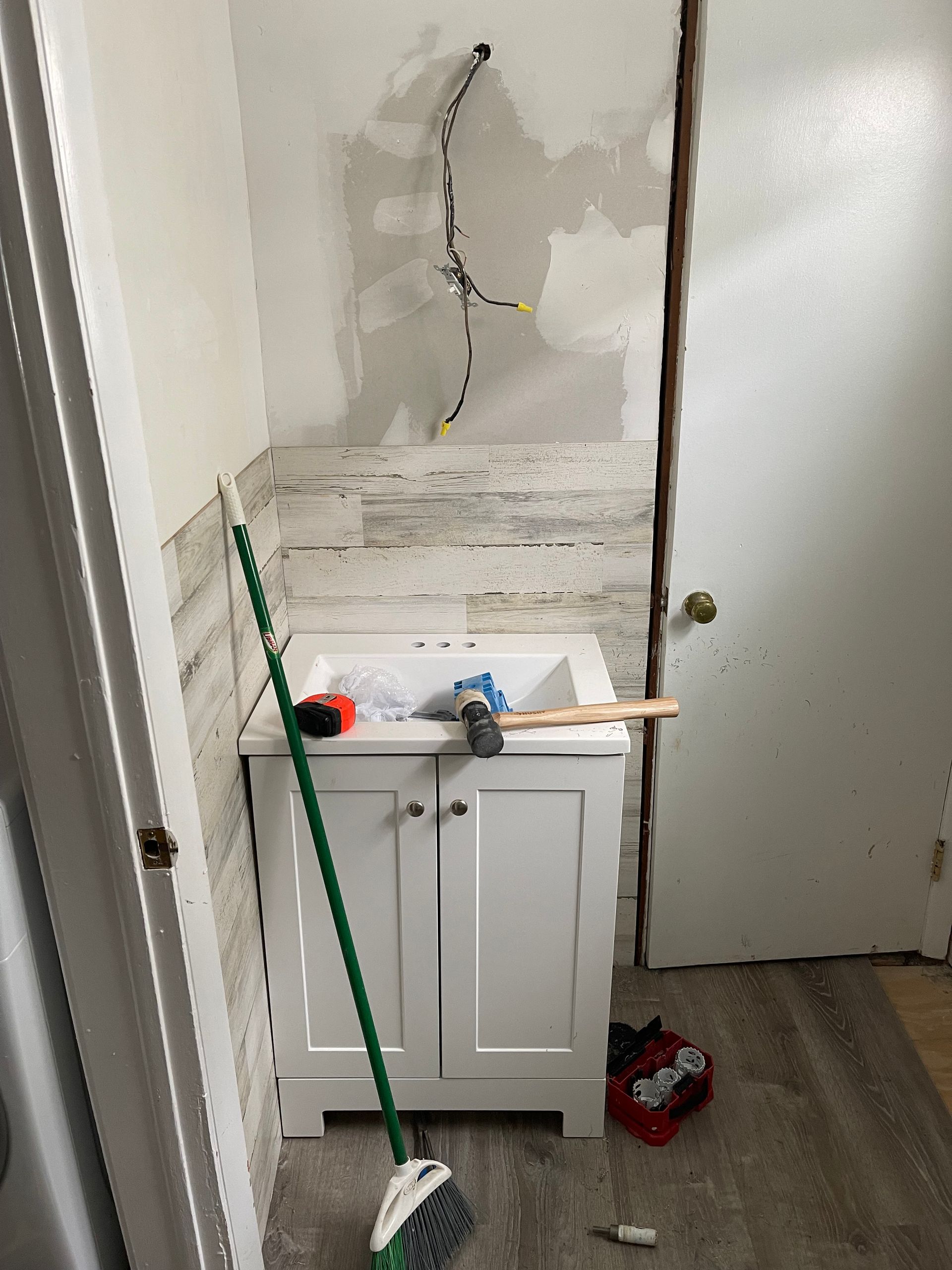 A bathroom with a sink and a broom on the floor.