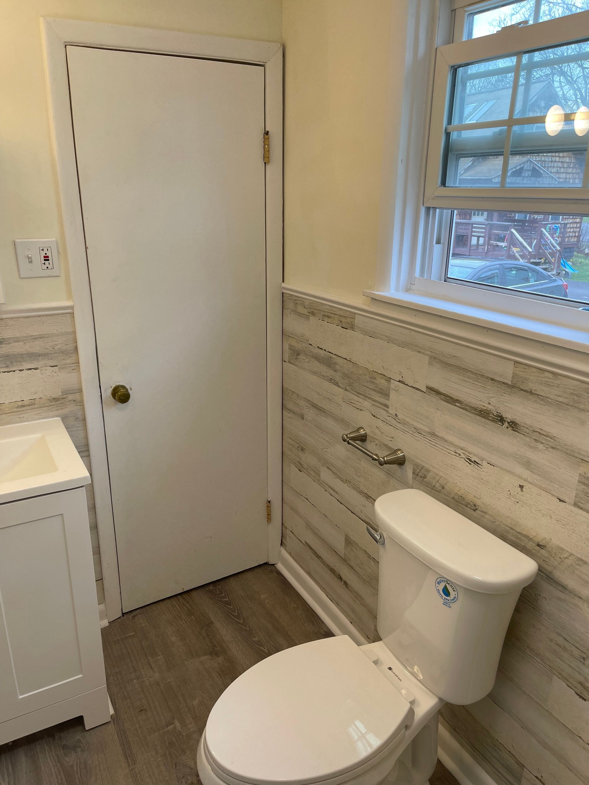 A bathroom with a toilet , sink and window.