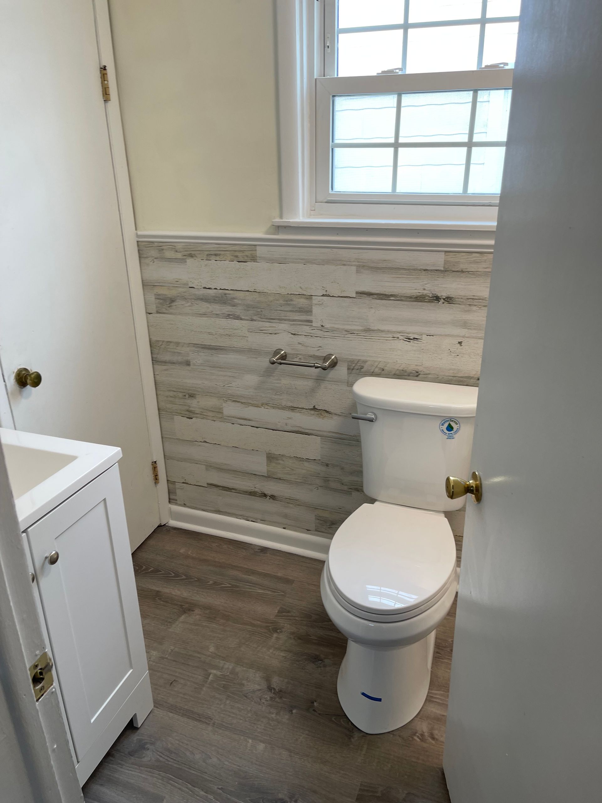 A bathroom with a toilet , sink , and window.