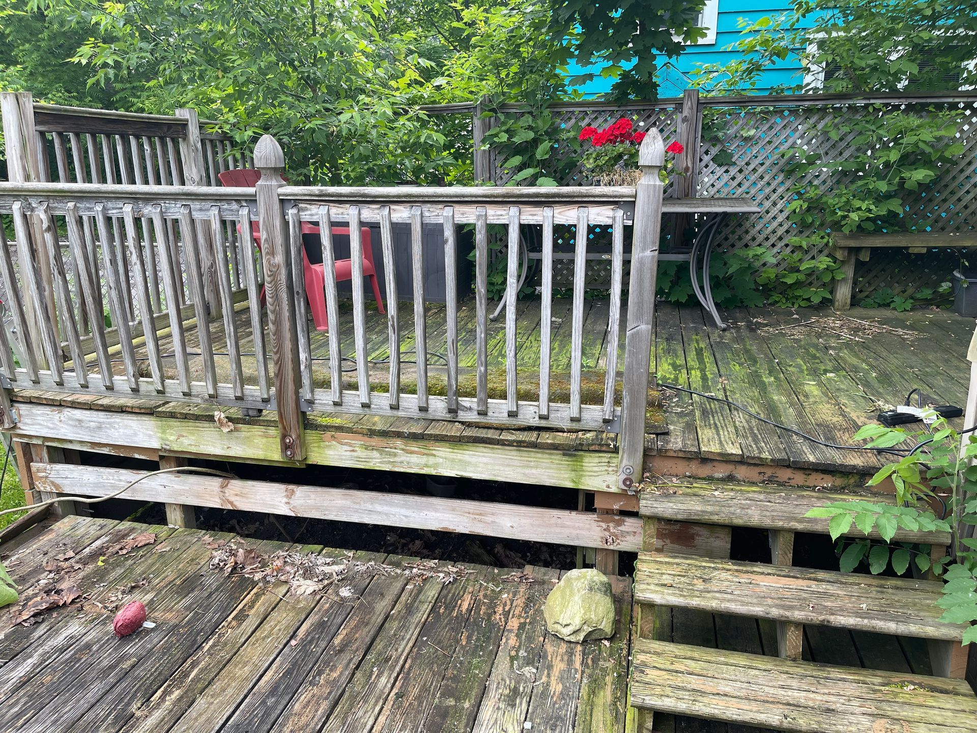 A wooden deck with a railing and stairs in a backyard.