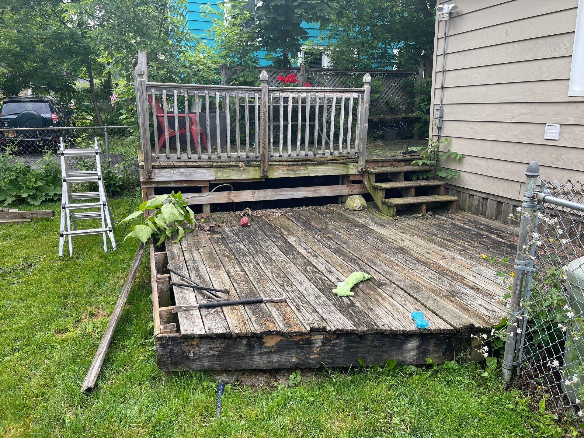 A wooden deck is sitting in the grass in front of a house.