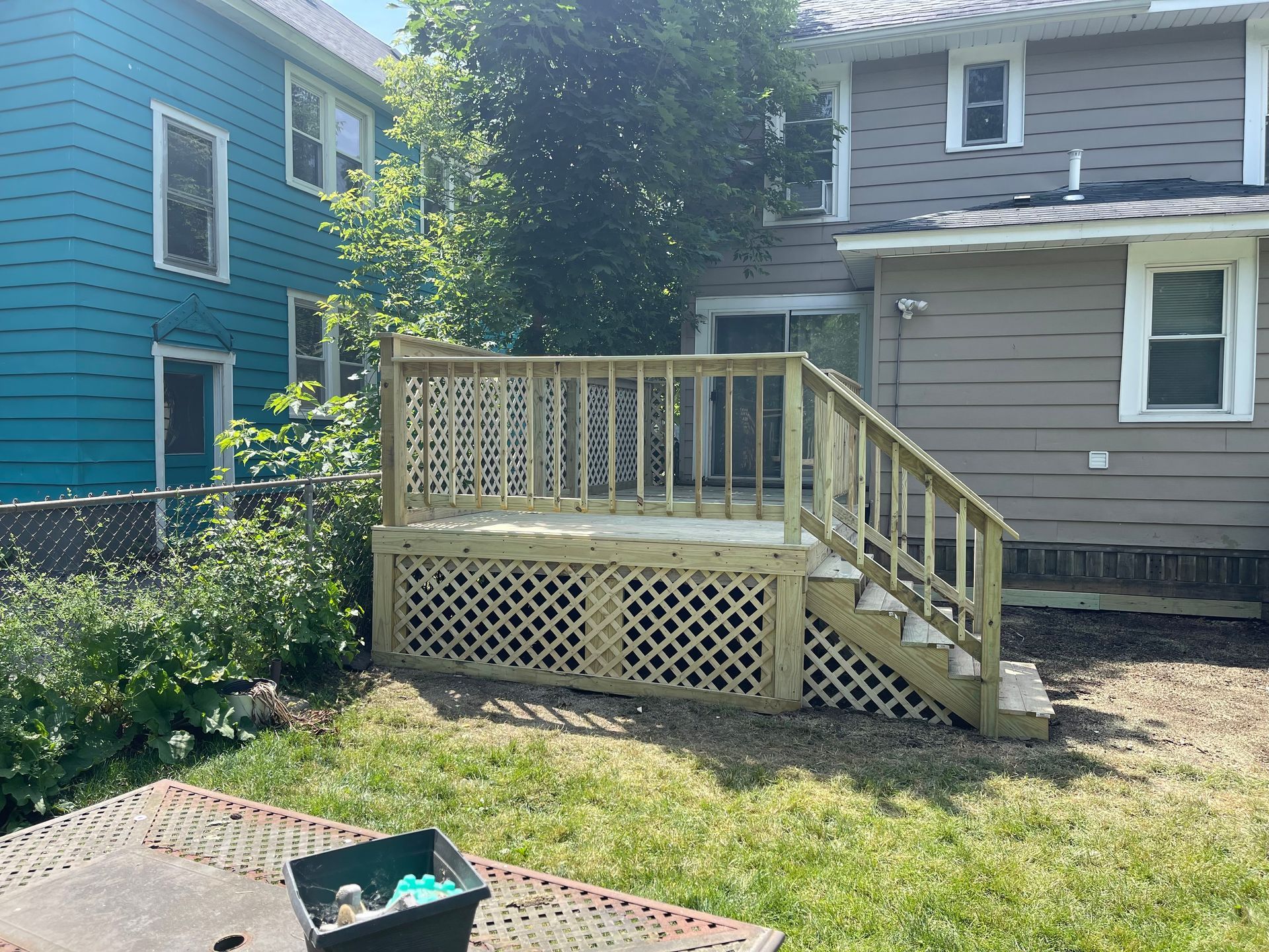 A wooden deck with stairs is in the backyard of a house.