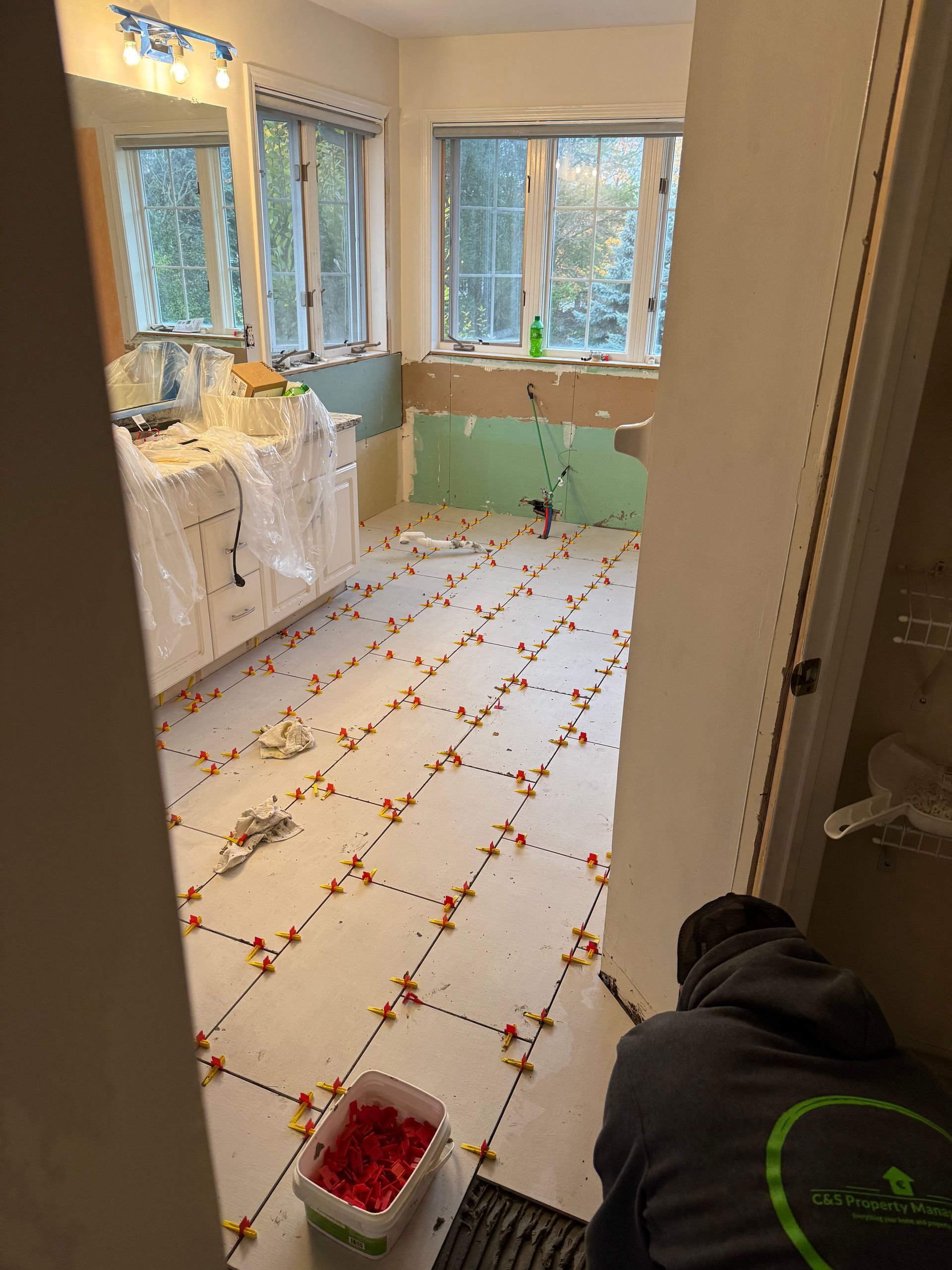 A man is laying tile in a bathroom.