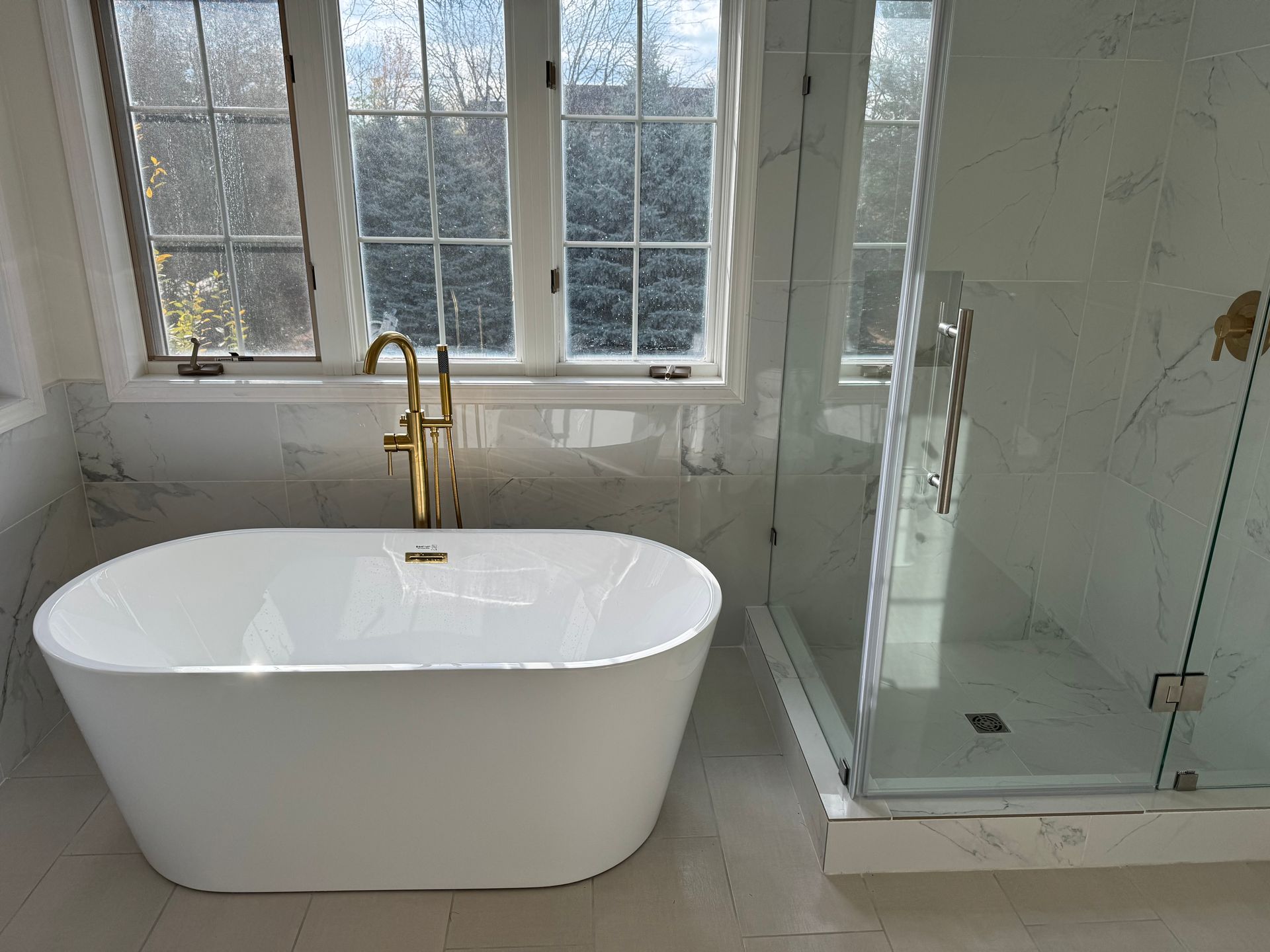 A bathroom with a bathtub , shower and window.